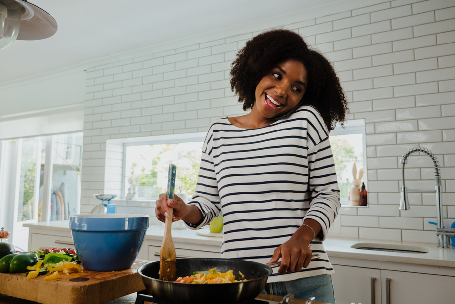 African american woman on phone while cooking food