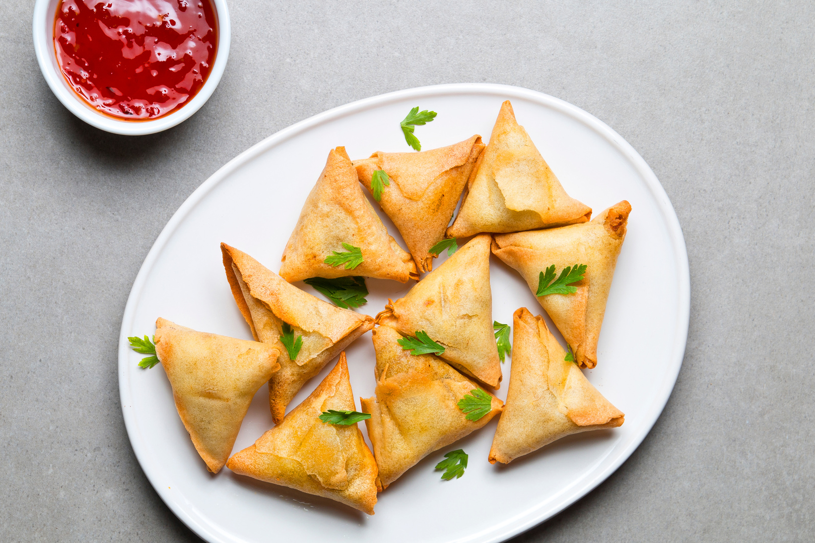 Plate vegetarian samosas on gray background